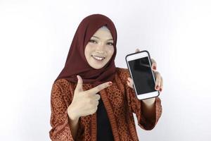 Young Asian Islam woman is smiling pointing on smartphone standing on white background.