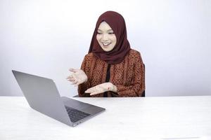 Young Asian Islam woman is smiling pointing hand when working on laptop on white background. photo