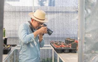 persona que trabaja en un invernadero, joven agricultor tomando fotos con su cámara en un jardín de cactus, conceptos de hobby.