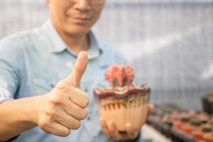 Man showing thumbs up with holding potted cactus photo