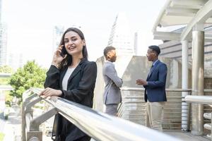 Business woman using communication device in city. Business team and teamwork concept. Business people standing outside in the city discussing about new project.