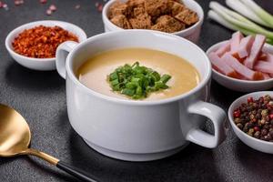 Cream soup with potatoes, leek and peas on a dark concrete table photo