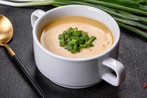 Cream soup with potatoes, leek and peas on a dark concrete table photo