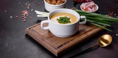 Cream soup with potatoes, leek and peas on a dark concrete table photo