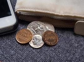 monedas de dólares estadounidenses colocadas fuera de la billetera con teléfono inteligente.