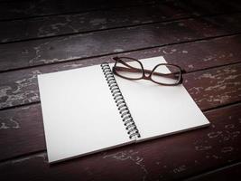 Workspace with glasses, note paper and notebook on old wooden table photo