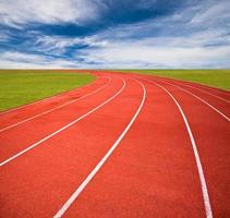 imagen conceptual de competición deportiva, pistas de atletismo con patio verde y cielo azul. foto