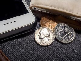 US dollar coins placed outside the wallet with smartphone. photo