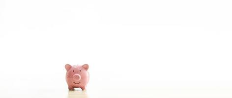 A pink piggy bank is placed on the table. The concept for financial, business, banking, save, loan, invest, budget, account, nobody, no people. Copy space on right for design or text white background. photo