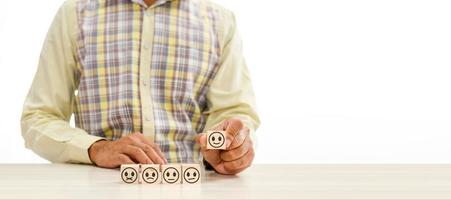 Hand holding wood cube face symbol icon to give satisfaction in service. rating very impressed. Customer service,  Satisfaction concept. Copy space, people, selective focus. White, blur background photo