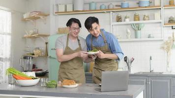 joven pareja gay sonriente cocinando juntos en la cocina en casa, lgbtq y concepto de diversidad. foto