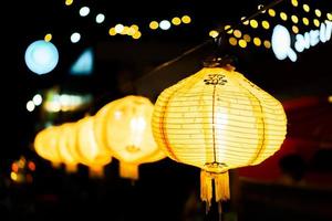 A row of yellow lanterns at night against a blurred background. photo