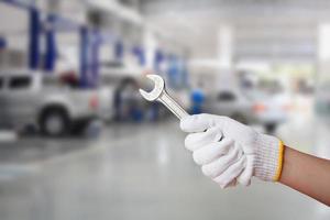 técnico sosteniendo una llave con fondo de centro de servicio de reparación de automóviles foto