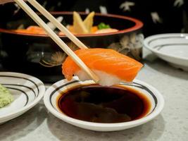 Salmon sushi in chopsticks dipping with soy sauce photo