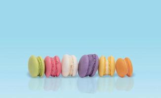 Mini various colorful pastel macarons on blue tabletop background photo