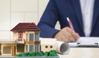 Focus at house model with blurred background of architect hand working on desk in office room photo