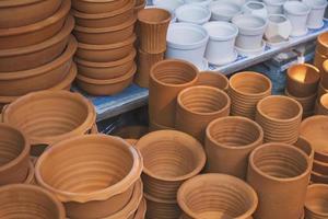 Stacks of various brown and white terracotta plant pots for sale in outdoor plant market photo