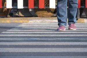 Front view of human legs walking across the street on zebra crossing in public area photo
