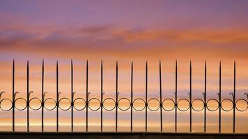 Silhouette arrow spiky metal fence against beautiful sunset sky background, front view with copy space photo