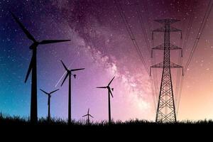 A silhouette of a windmill used to generate electricity in a field against a beautiful Milky Way backdrop. photo