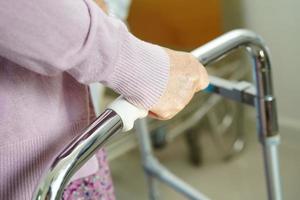 Asian elderly woman disability patient walk with walker in nursing hospital, medical concept. photo