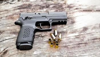 Automatic 9mm black pistol gun and bullets on wooden table. photo