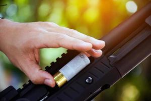 A shotgun shooter is loading a shot into the barrel of a long shotgun. photo