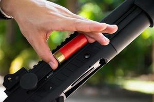 A shotgun shooter is loading a shot into the barrel of a long shotgun. photo