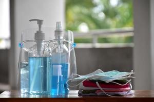 Covid 19 protective equipments on table, facemask, hand sanitizing gel, faceshield, alcohol gel, photo