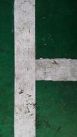 Close up of a chapped-white line drawn on a green-broken floor at public sports field. photo