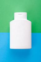 White blank plastic bottle on blue and green background.
