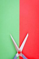 Minimalist image of scissors on red and green background.