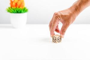 Hand holding wood cube face symbol icon to give satisfaction in service. rating very impressed. Customer service,  Satisfaction concept. Copy space, vase, tree, selective focus. White, blur background photo
