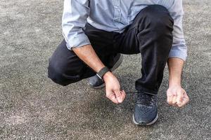 A man wears jeans tying black shoelaces in the sunlight on a sunny day in the park. selective focus, Closeup, Copy space, Blurred background photo