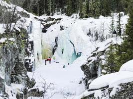 Ice climbers mountaineers climb up frozen waterfall Rjukandefossen, Hemsedal, Norway.
