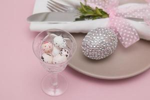Glass with Easter eggs on the background of plates and cutlery. Variative focus photo