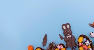 Banner Easter eggs hunt sweets concept with chocolate bunny on blue background copy space photo