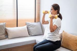 mujer asiática joven atractiva y saludable haciendo ejercicio en casa durante el entrenamiento con ropa cómoda en una alfombra en su sala de estar, concepto de estilo de vida saludable