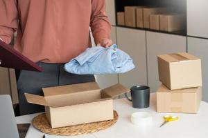 Asian business owner working at home with packing box of his online store prepare to deliver products to customers, alpha generation life style concept. photo