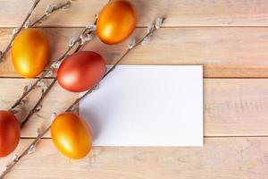 huevos de Pascua dorados y tarjeta de felicitación sobre fondo de madera. foto