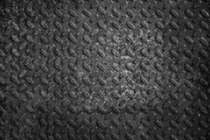 Old and rusty metal floor in black and white. Texture of a rough metal sheet with a convex pattern.