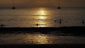 beau coucher de soleil avec des silhouettes de personnes profitant de l'océan. video