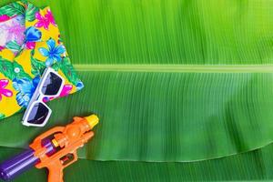 Songkran Festival background with jasmine garland Flowers in a bowl of water, perfume and limestone on a green wet banana leaf background. photo