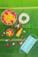 Songkran Festival background with jasmine garland Flowers in a bowl of water, perfume and limestone on a green wet banana leaf background. photo