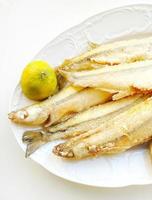 Fried small sea fish with lime lemon on a platter photo