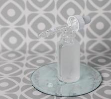 Cosmetic glass bottle with pipette on tile background photo