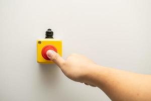 detener el botón rojo y la mano del trabajador a punto de presionarlo. botón de parada de emergencia. gran botón rojo de emergencia o botón de parada para presionar manualmente. foto