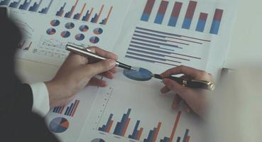 Close-up of two women's hands pointing to a turnover chart while talking on a wooden table in the office. group support concept photo