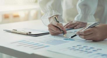 Close-up of two women's hands pointing to a turnover chart while talking on a wooden table in the office. group support concept photo