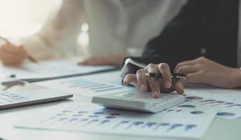 Close up businesswoman using calculator with businesswoman analysis on data paper  at the office photo